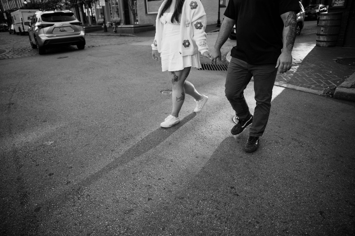 People walk past a storefront shown in black and white film photography capturing an urban street scene.