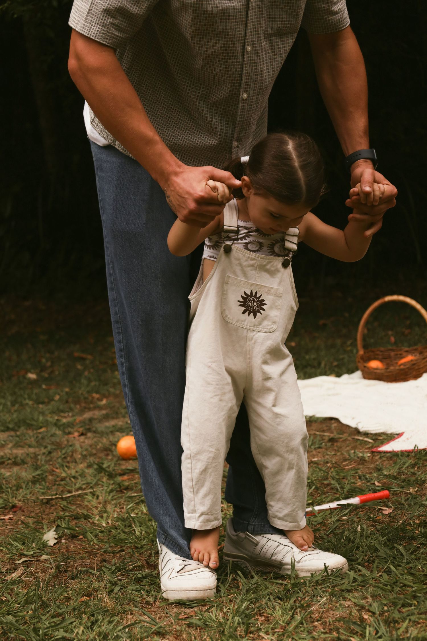 Close-up view of someone's legs wearing white shorts and sneakers while standing on grass with pumpkins nearby.