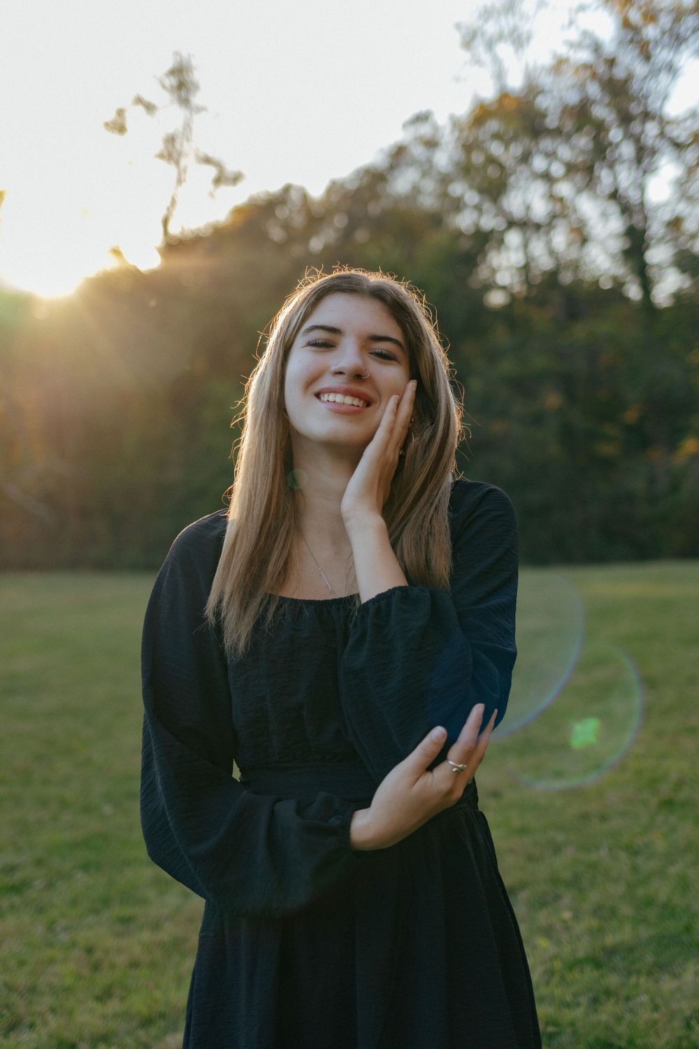 A candid moment captured of someone in dark clothing laughing joyfully in a sunlit field.