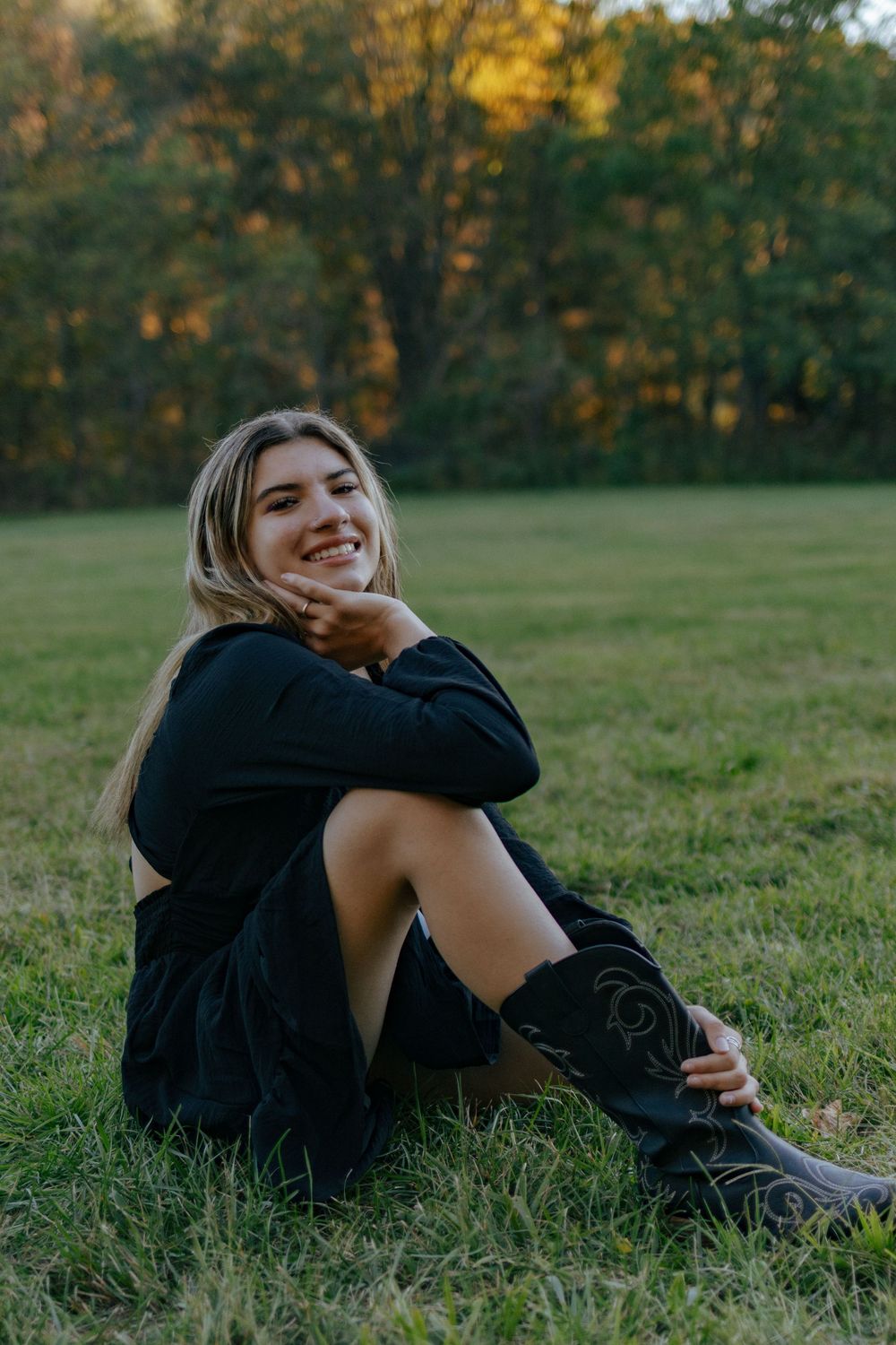 A person in dark clothing relaxes on grass during a sunset photoshoot.