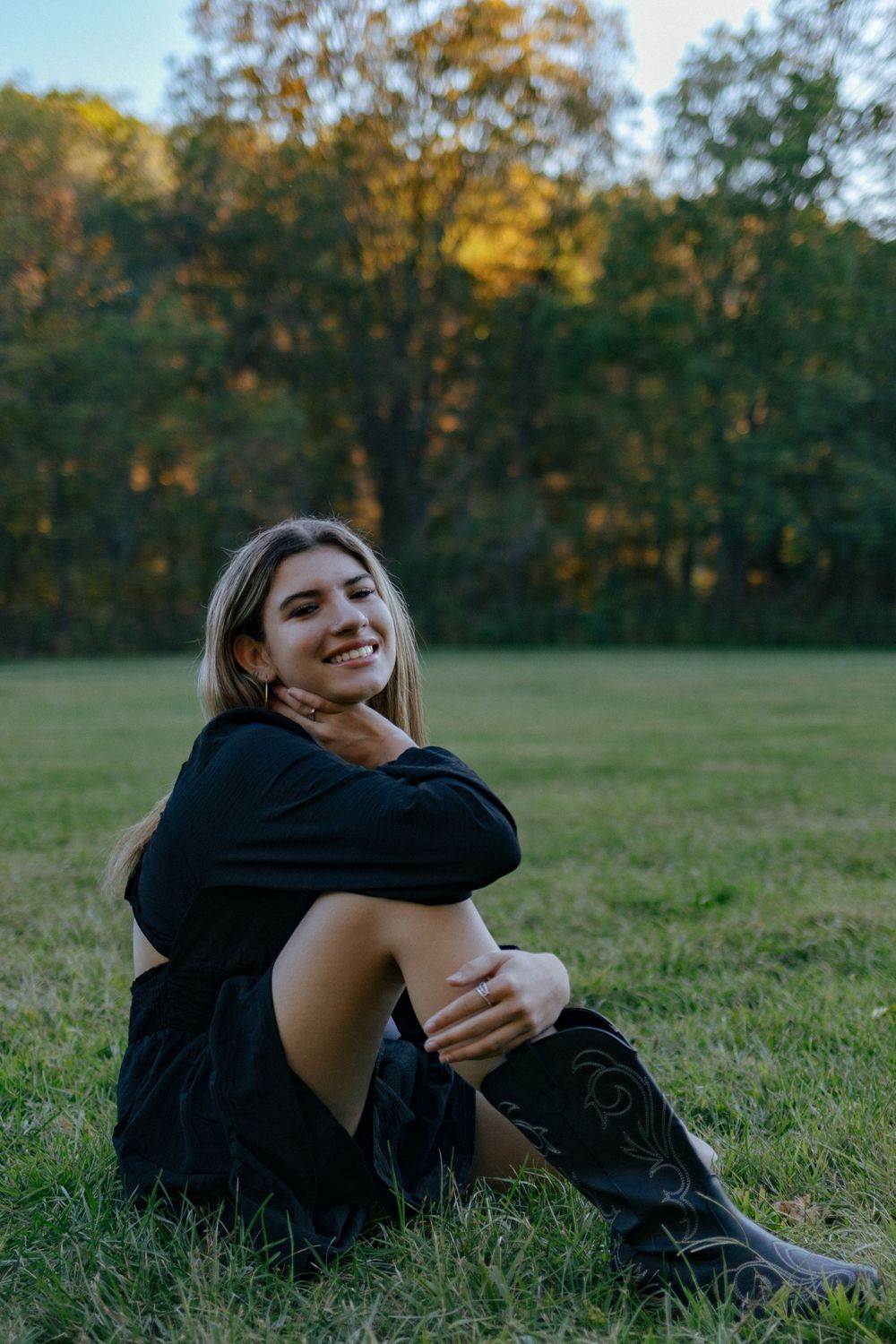A casual outdoor portrait of someone resting on grass during golden hour.