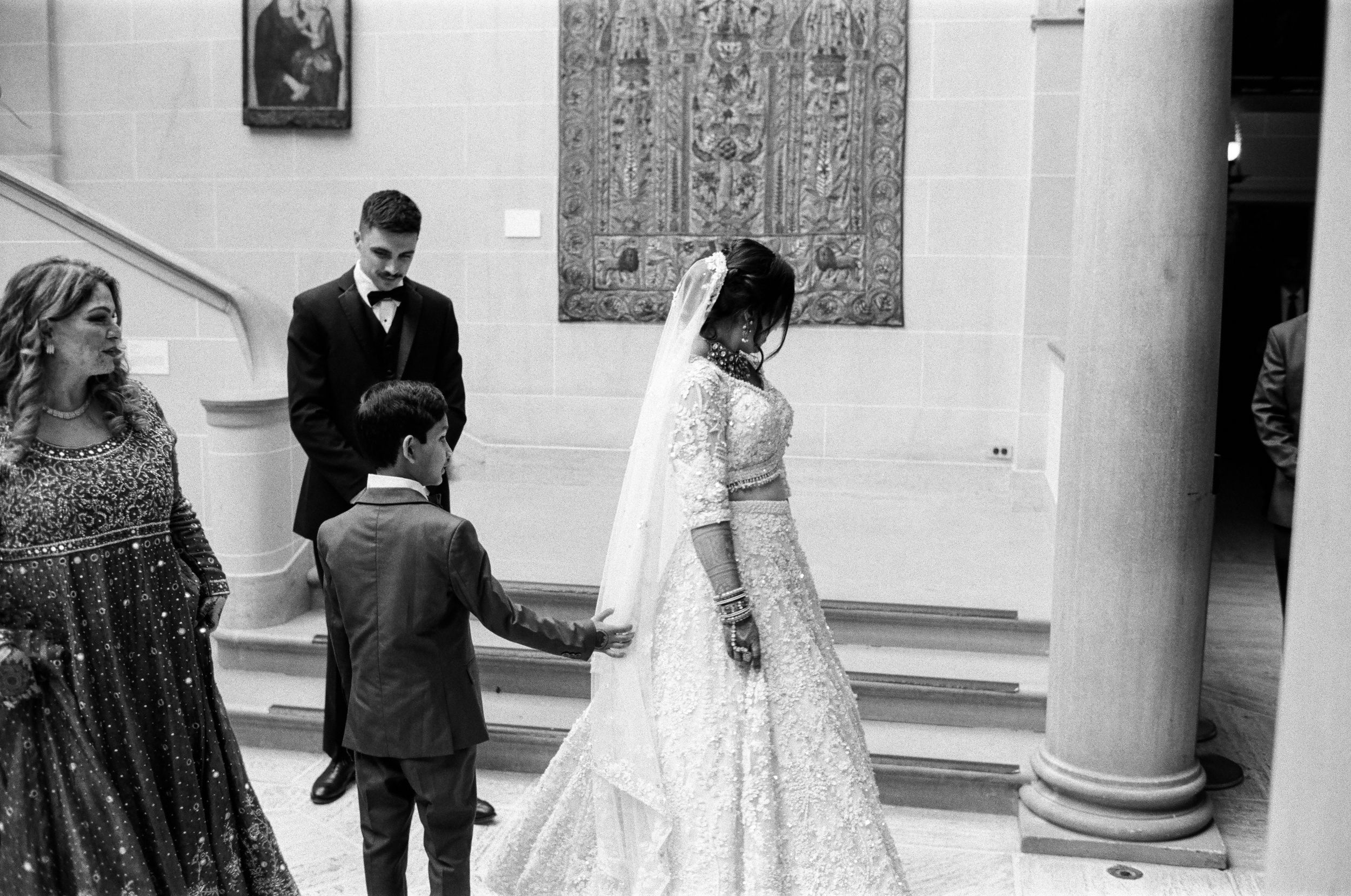A film photo of a young boy looking at a bride's wedding dress at Cuneo Mansion.
