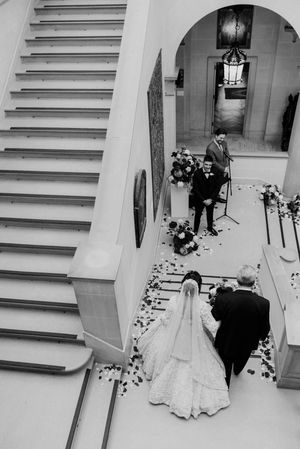 A bride is escorted down a staircase during an Indian fusion wedding ceremony at Cuneo Mansion.