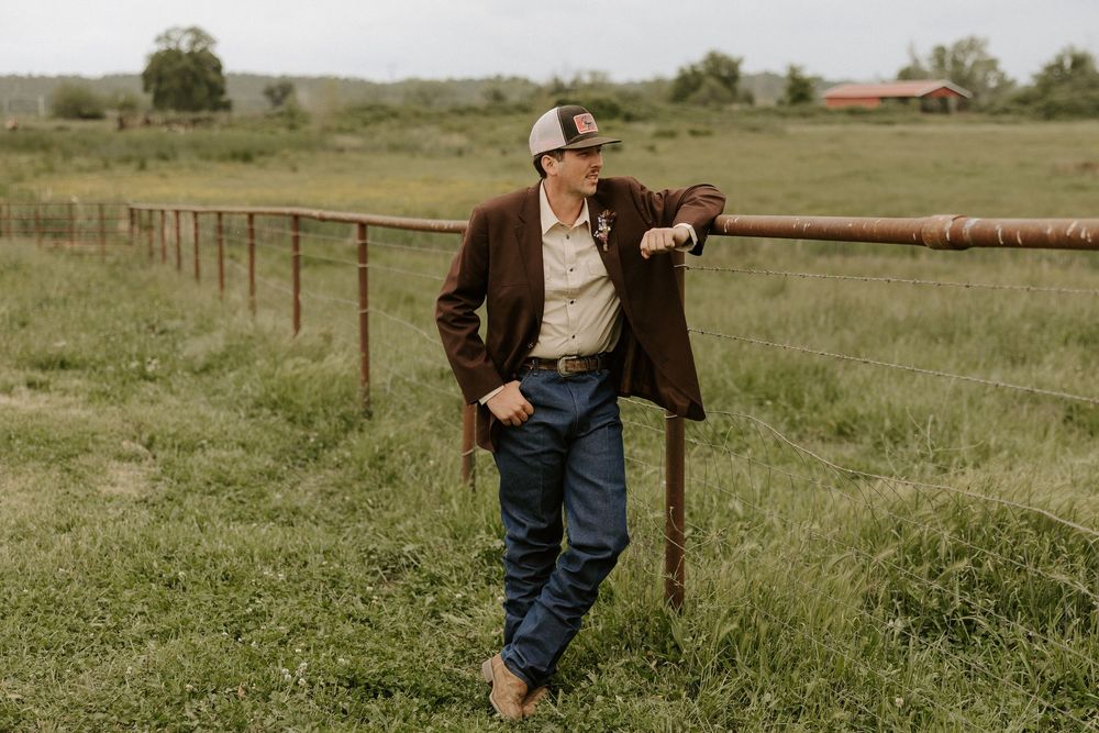 A rustic wooden fence stretches across rolling green pastures on a rural countryside property.