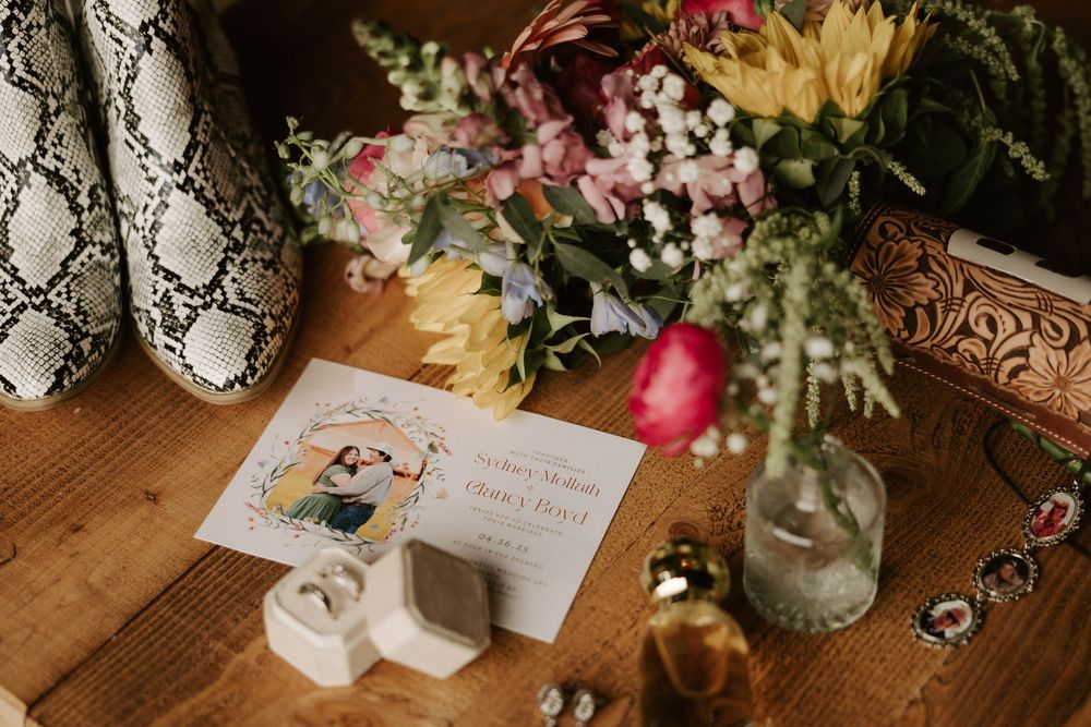 Rustic wedding reception table setting with vintage decor, fresh flowers in glass vases, and handwritten place cards.
