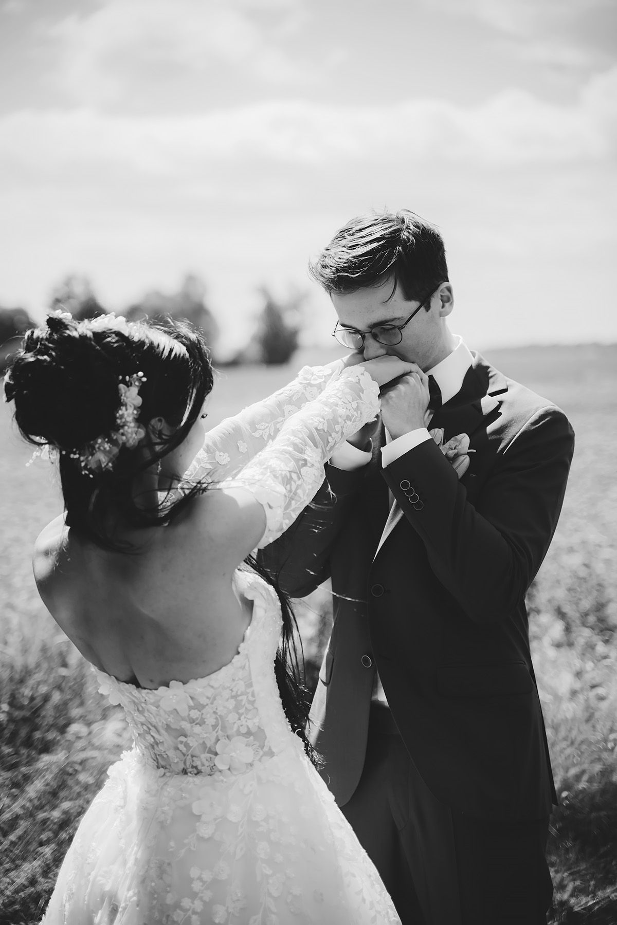 Bröllopsporträtt på en äng, mannen kysser brudens händer. Bröllopsfotograf Josefin Landhagen i Östergötland, Lets Bloom Media.
