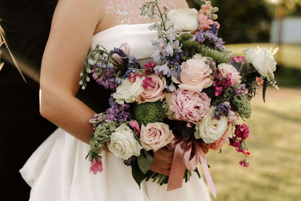 Elegant bridal bouquet featuring blush roses, white flowers and deep burgundy blooms with cascading greenery.