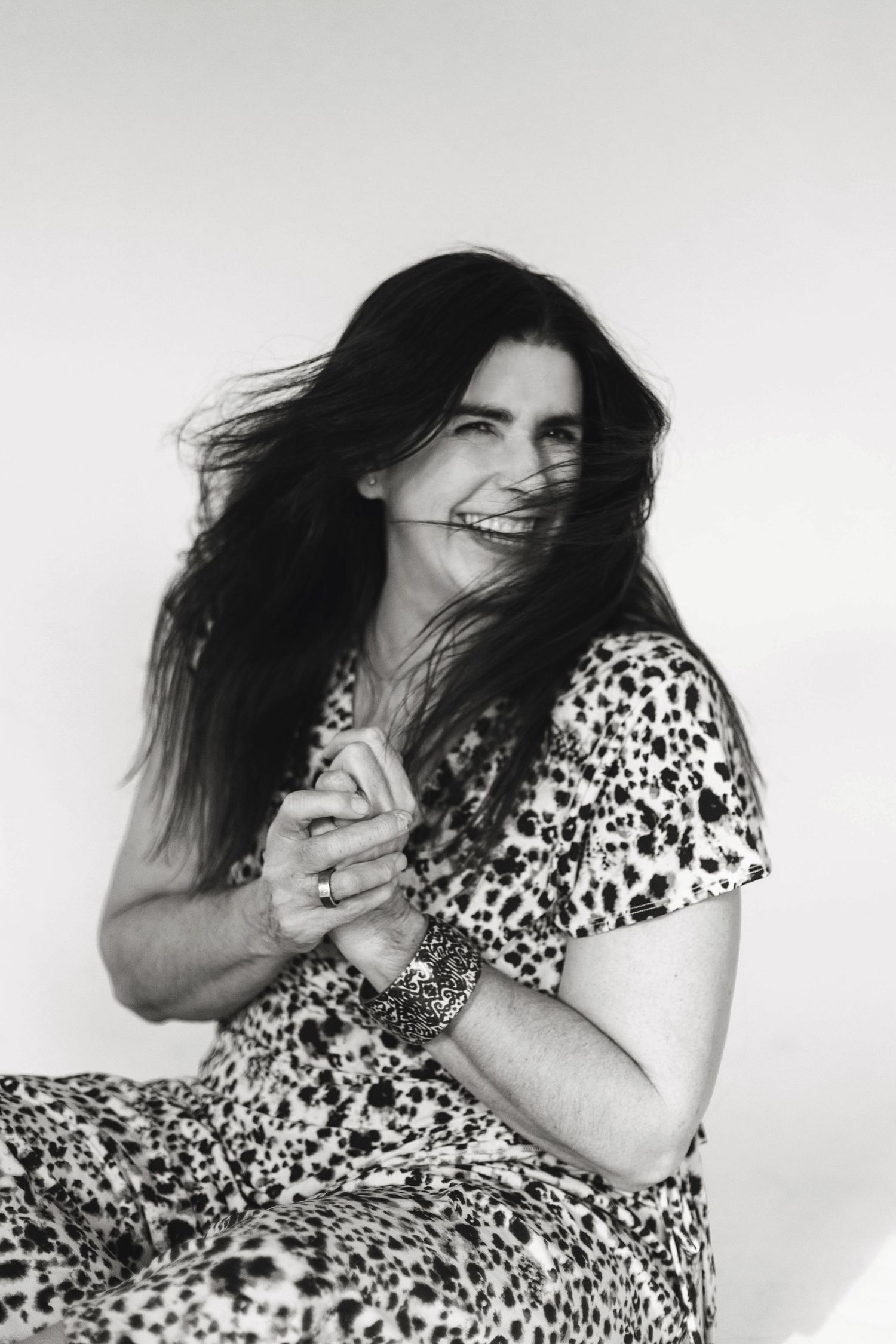 A person in a black and white polka dot dress poses expressively against a white background in a dynamic photo series.