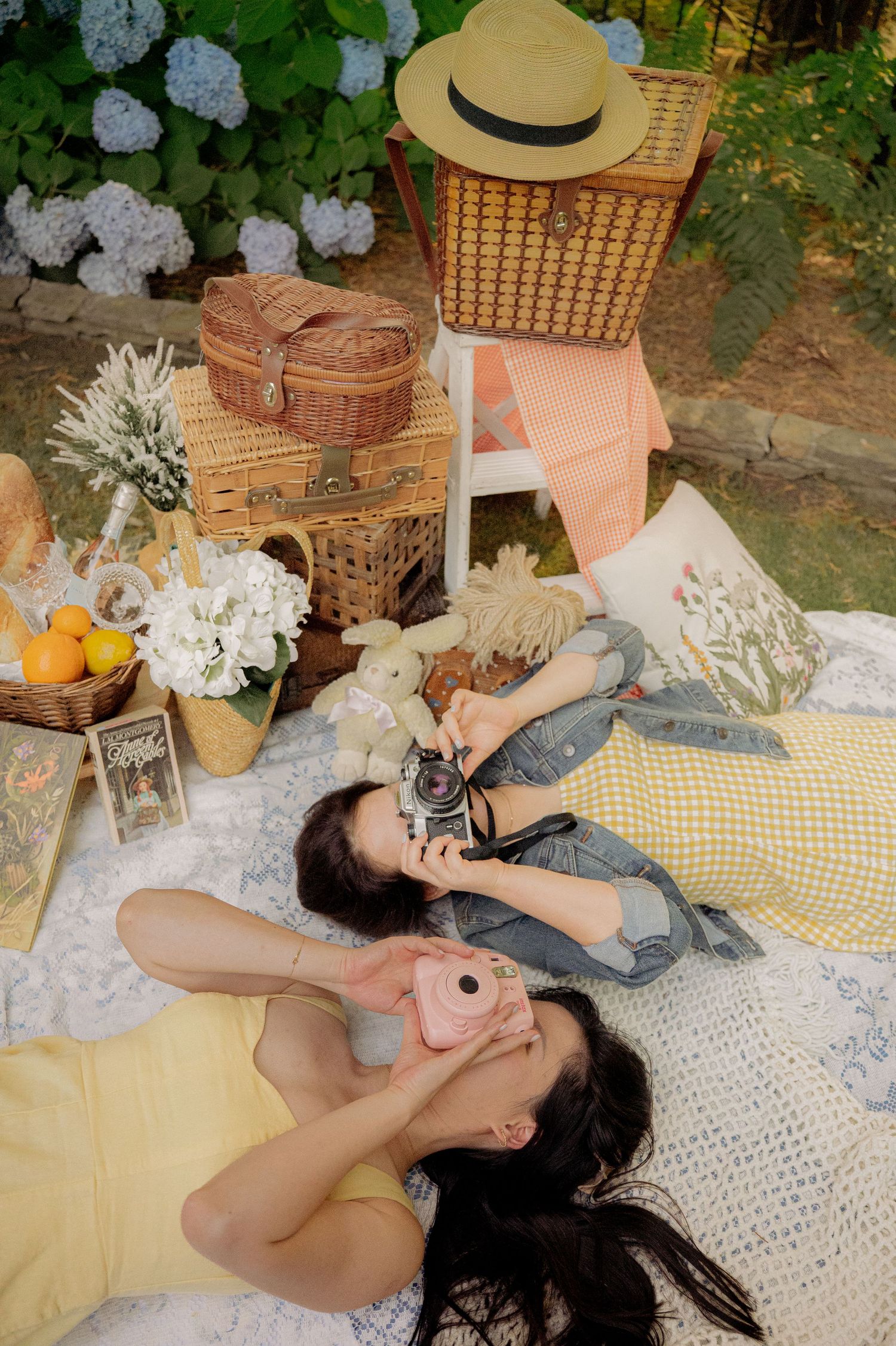 Outdoor picnic scene with vintage baskets, blankets and lace decorations arranged on the ground.