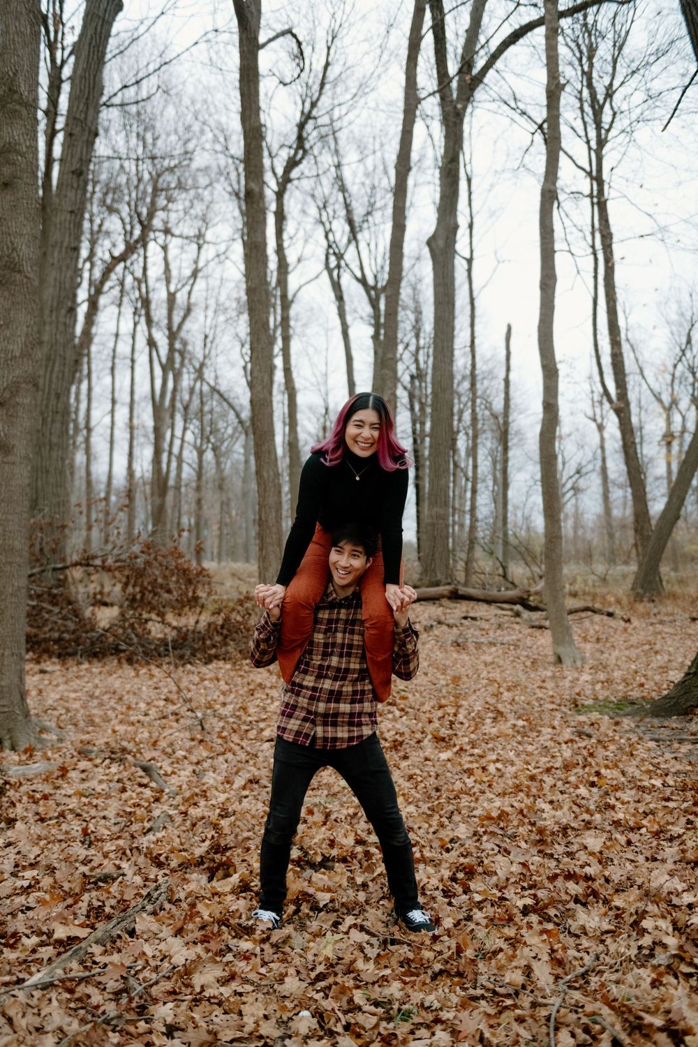 A sequence of playful poses in a forest covered with fallen autumn leaves and bare trees.