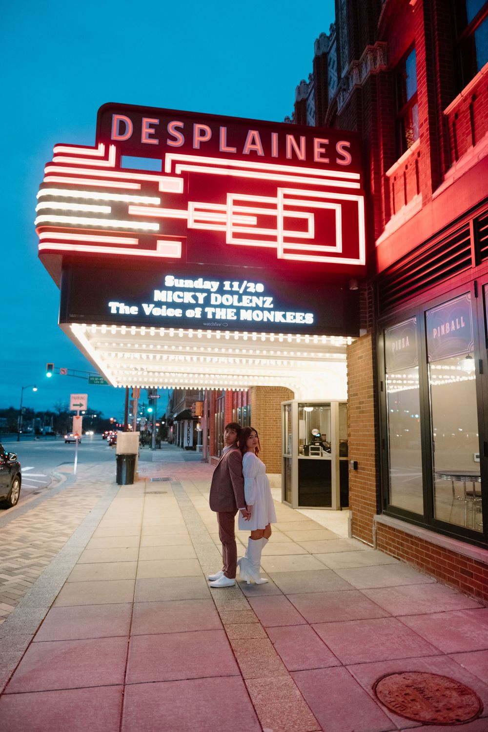 Exterior shots of the Des Plaines Theater at night with illuminated marquee and neon signage glowing against a dark sky. Surprise Proposal