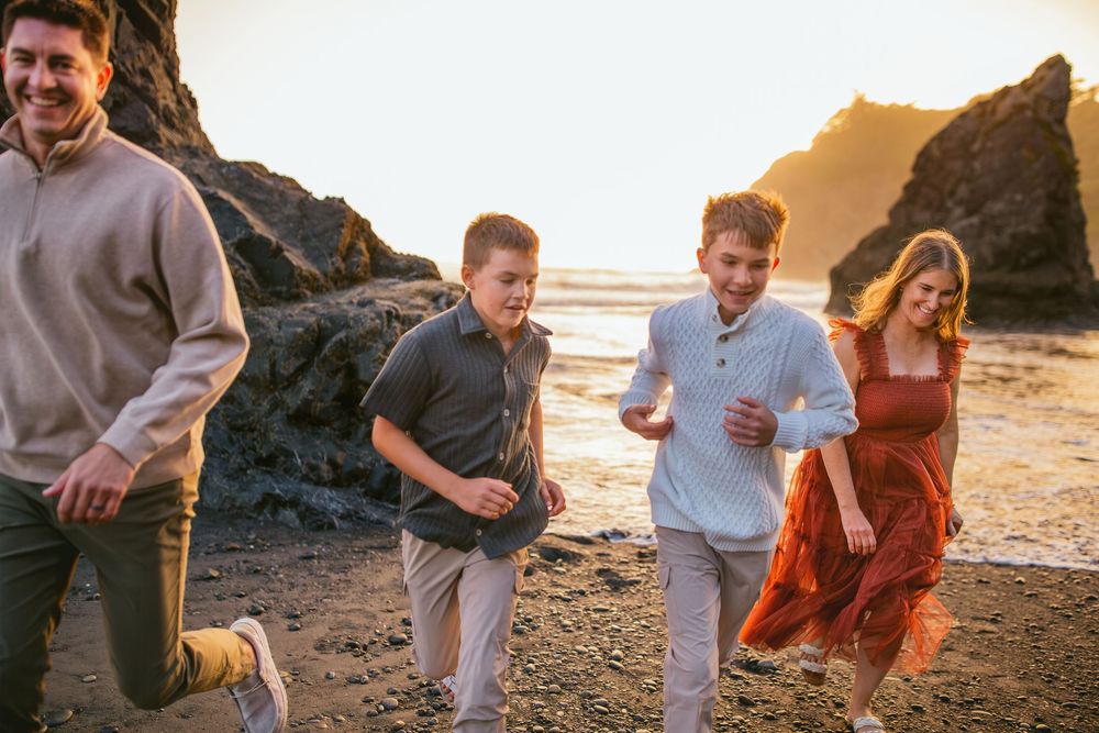 Family joyfully running during their family adventure photography session at Ruby Beach in Olympic National Park near Seattle, Washington