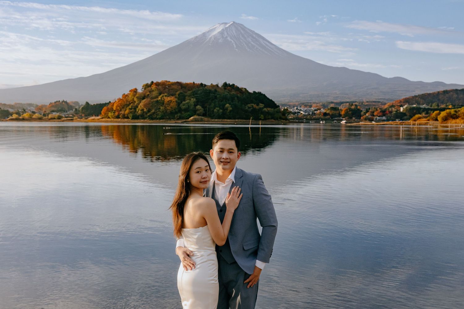Mount Fuji rises majestically over a serene lake in Japan during autumn with colorful foliage reflections.