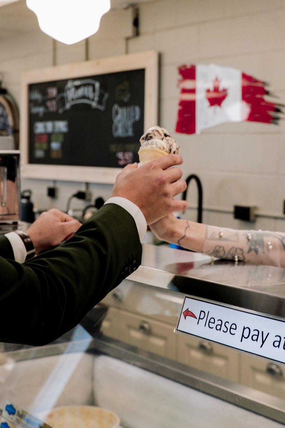 A series of hands passing cash across a counter at a retail payment station, showing a transaction in progress.