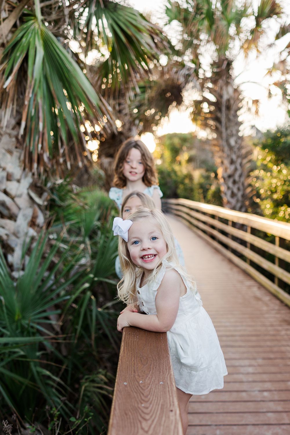 A series of photos on a wooden boardwalk surrounded by palm trees and tropical foliage at sunset.