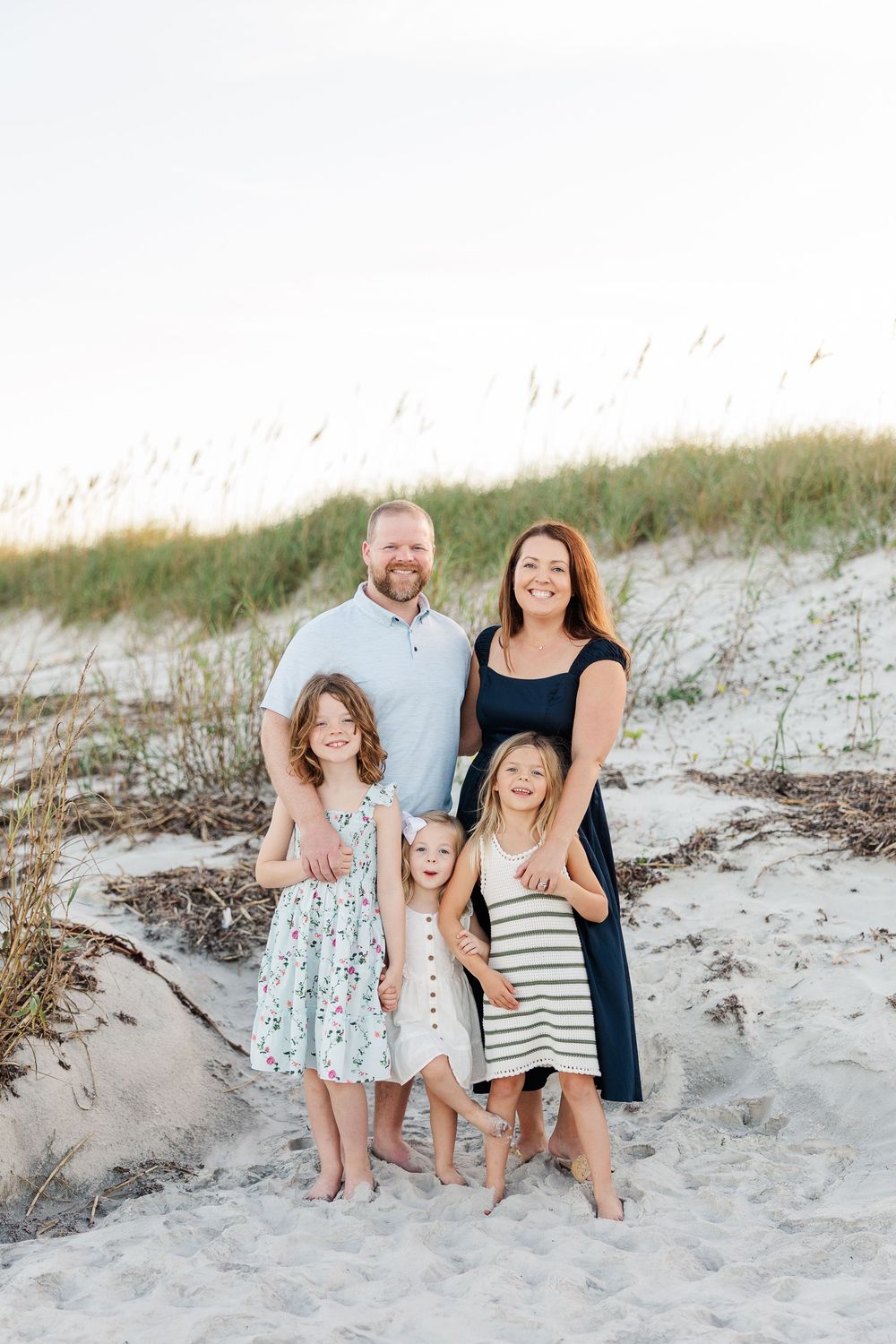 A family portrait series captured in the sand dunes at the beach during golden hour.