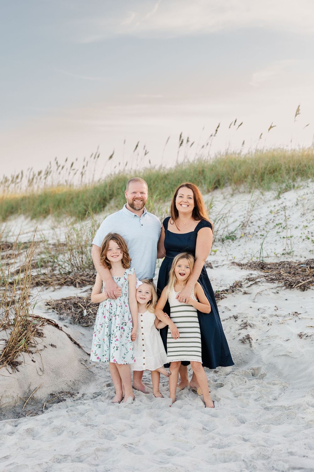Group enjoying a sunny day together on white sand dunes with sea oats swaying in the breeze.