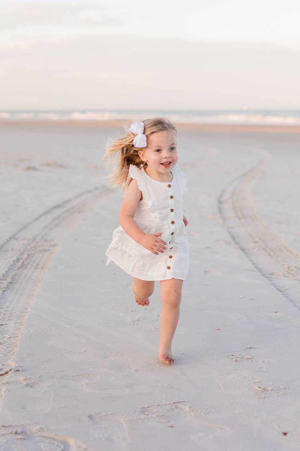 A sequence of joyful moments captured on a sandy beach with soft lighting and footprints in the sand.