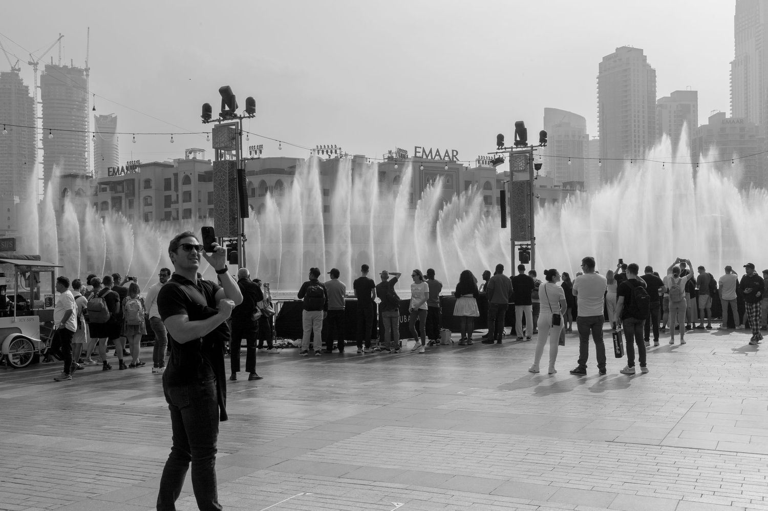 People stroll through a fountain plaza with Chicago's iconic skyline silhouetted against a misty backdrop.
