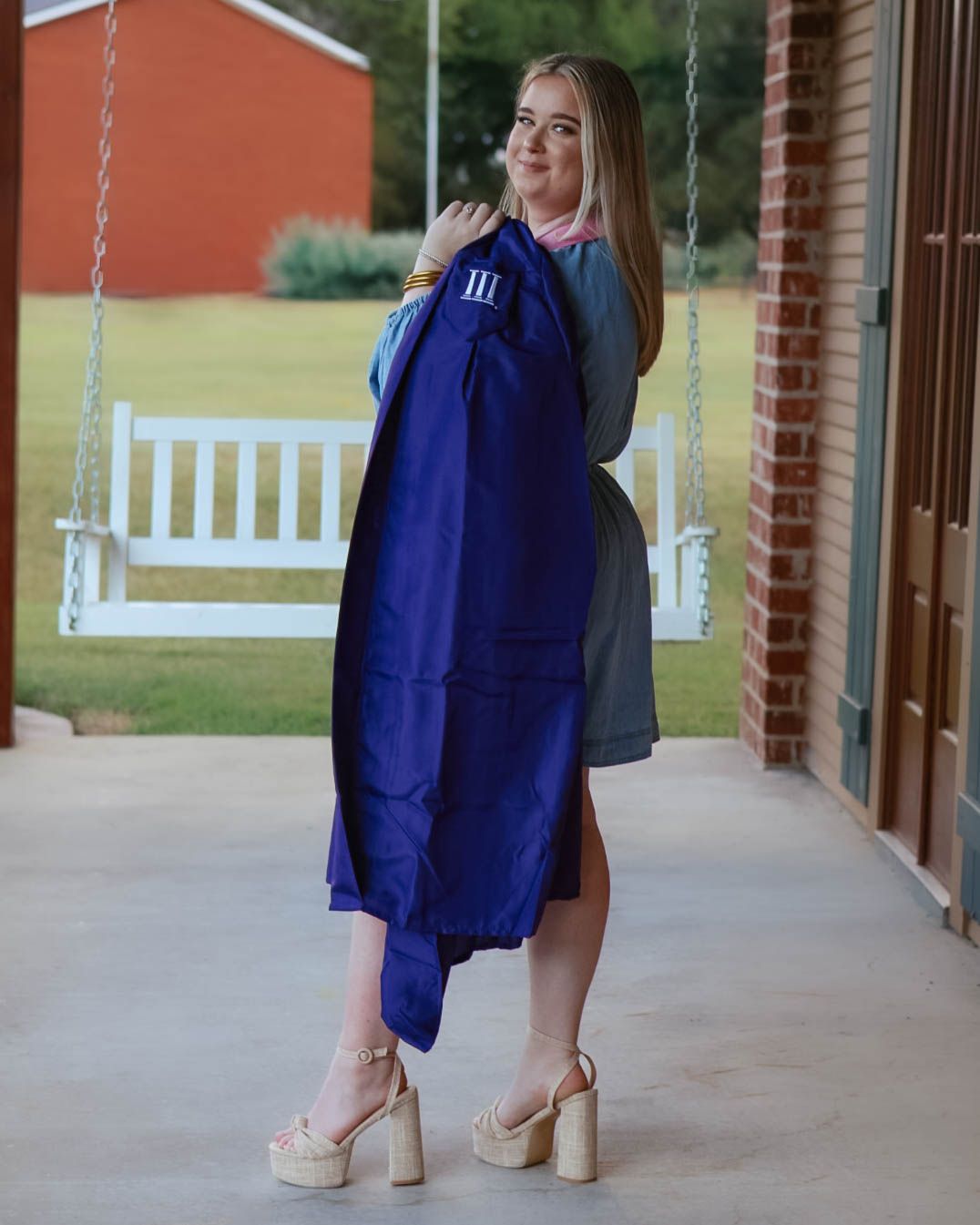 Casual poses on a porch with white swing wearing navy blue outfit.