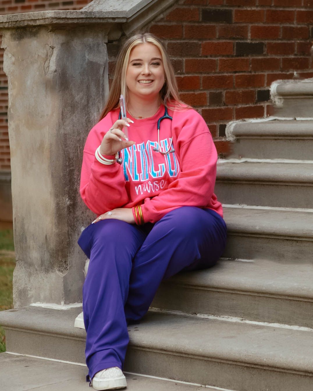 Someone wearing pink and purple loungewear sitting casually on concrete steps.