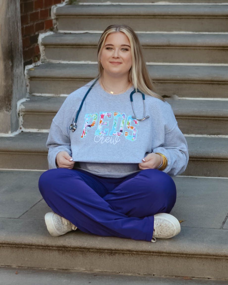 Casual portrait series on brick steps wearing a gray sweatshirt and navy pants.
