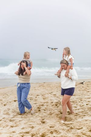 Family members playfully posing and making silly faces on a sandy beach.