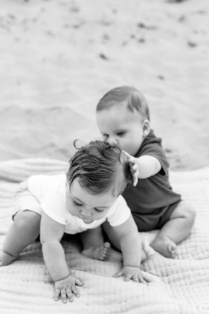 Black and white photo series showing a baby crawling and exploring on a textured blanket.