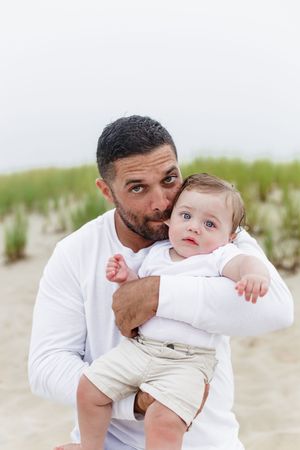 Sweet moments captured between parent and baby on a sandy beach.