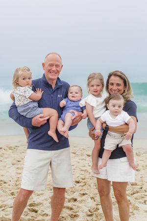 Group portrait of adults holding young children on a misty beach.