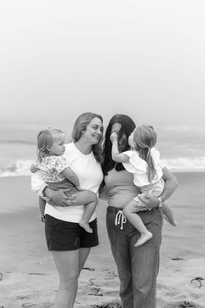 Family members embrace and share playful moments together on an overcast beach.
