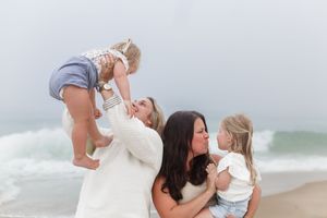 A joyful family moment at the beach with crashing waves in the background.