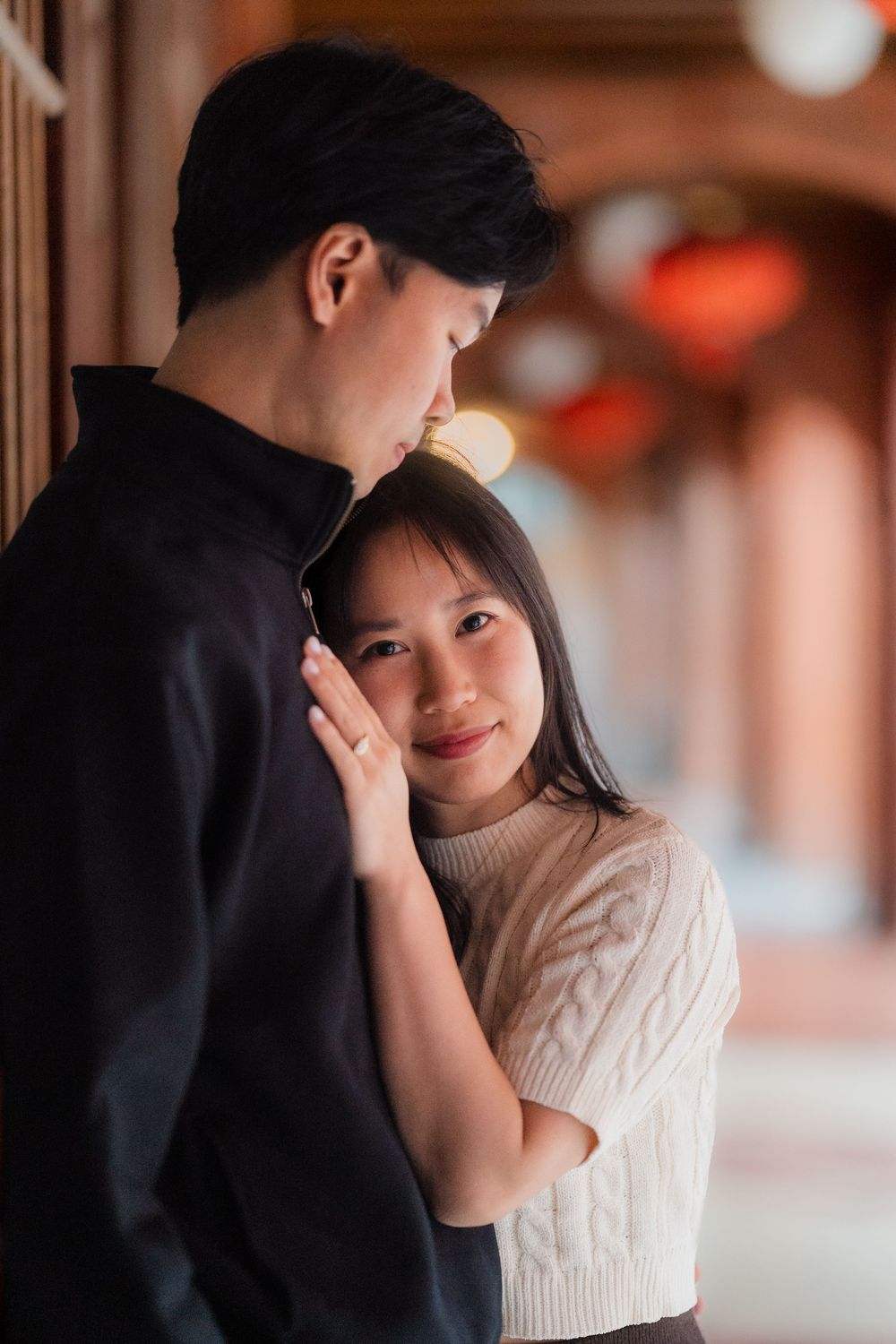 A romantic couple shares intimate moments in a warm-lit hallway with red lanterns creating an atmospheric glow.