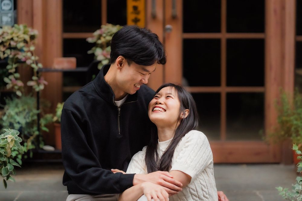 A couple shares romantic moments in a garden setting wearing black and white outfits.