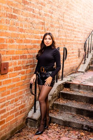Fashion photo against rustic brick wall showing modern urban style with black attire.