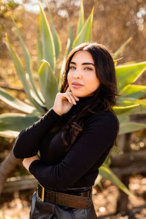 Autumn outdoor fashion portrait with agave plants and black outfit in natural lighting.