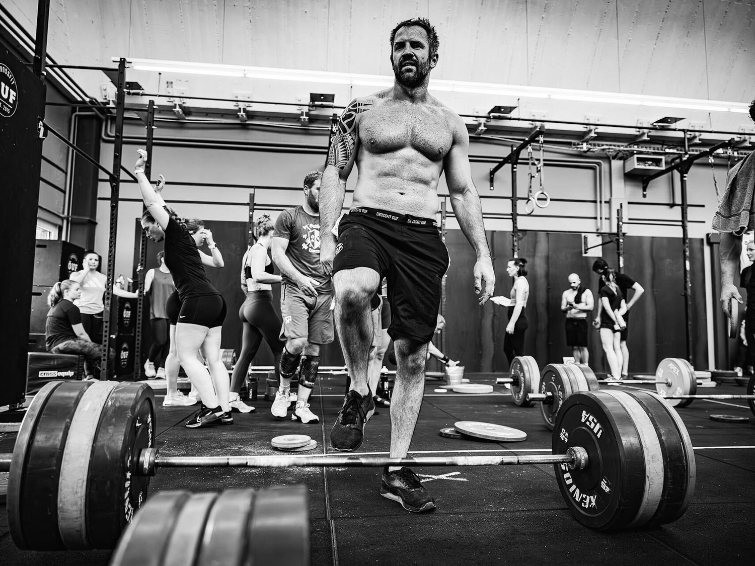 Athletes training in an intense CrossFit workout session at a gym with heavy weights.