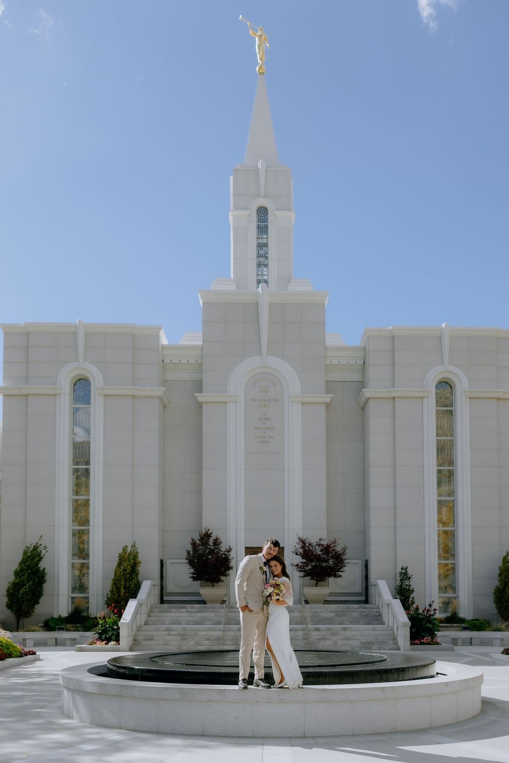 White marble exterior of the Baton Rouge Louisiana Mormon Temple with spire and fountain on a sunny day.