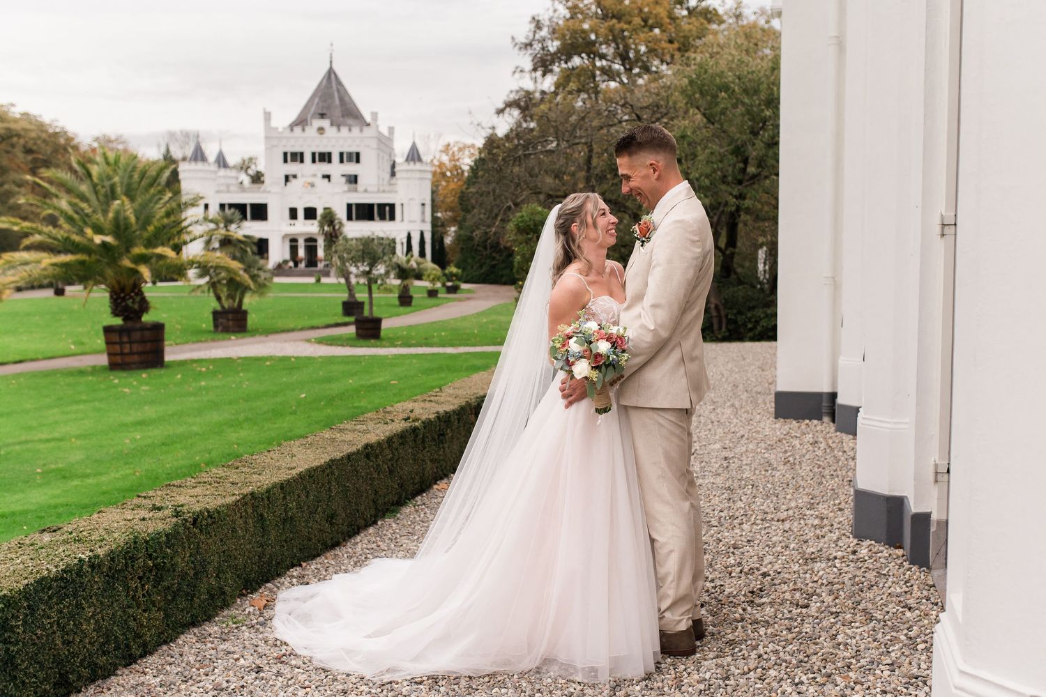 Bruid en bruidegom lachten naar elkaar tijdens de fotoshoot op oranjerie sandenburg