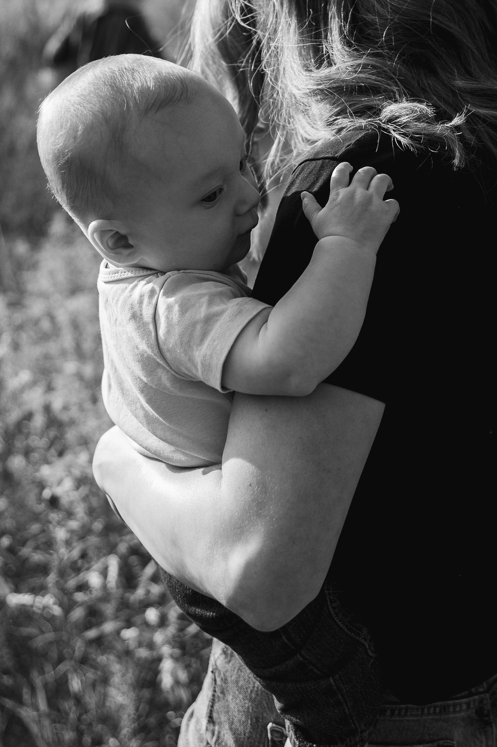 Black and white photos show a tender moment between parent and baby in an intimate embrace.