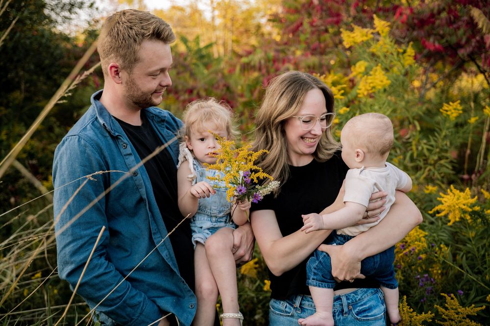 A family shares joyful moments together in a garden filled with vibrant fall foliage and golden sunlight.