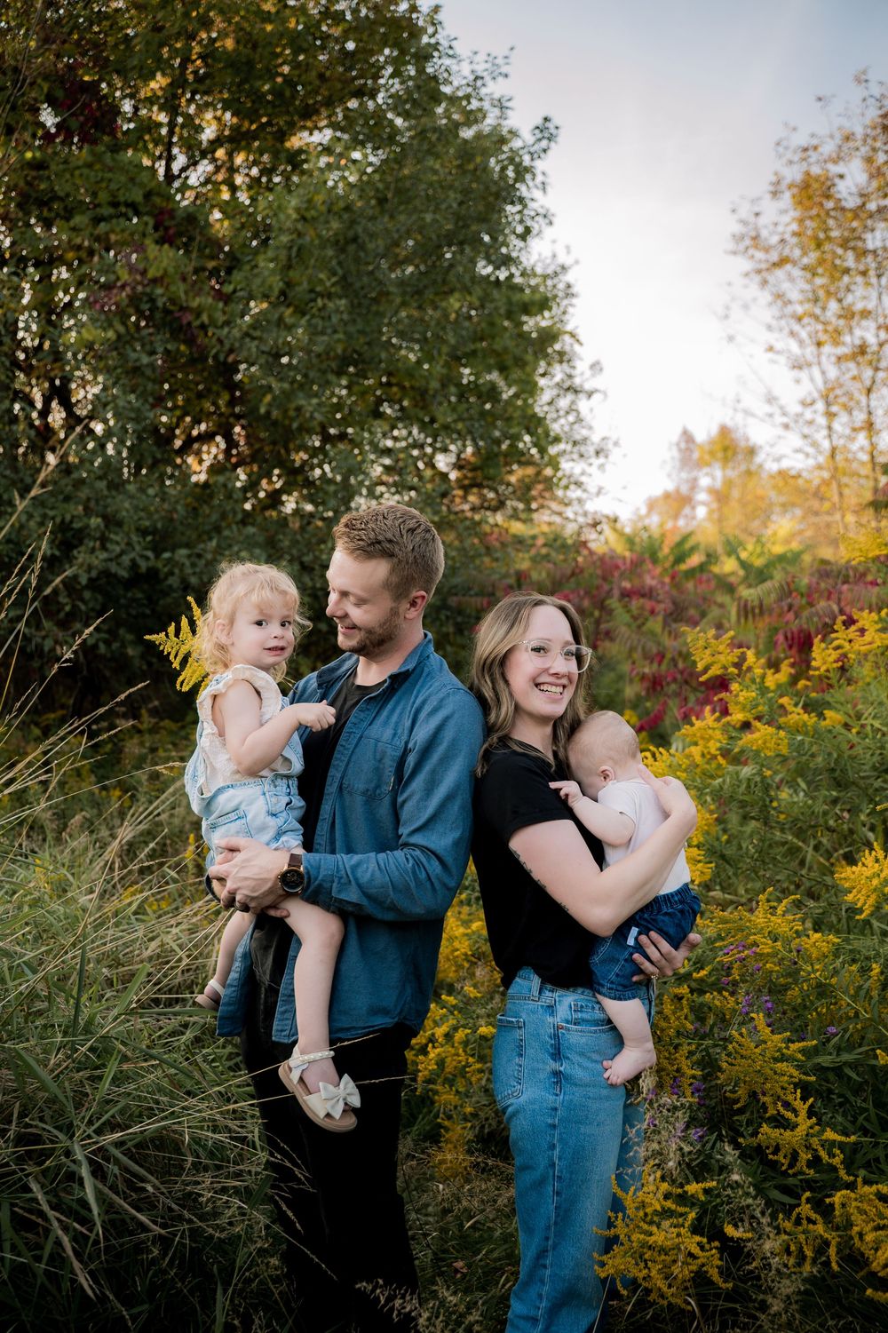 A family shares joyful moments together in an outdoor setting with autumn foliage and golden light.