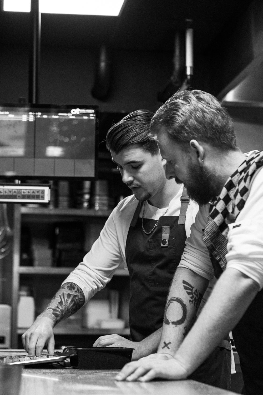 Restaurant chefs working together in a professional kitchen preparing dishes with focused attention to detail.