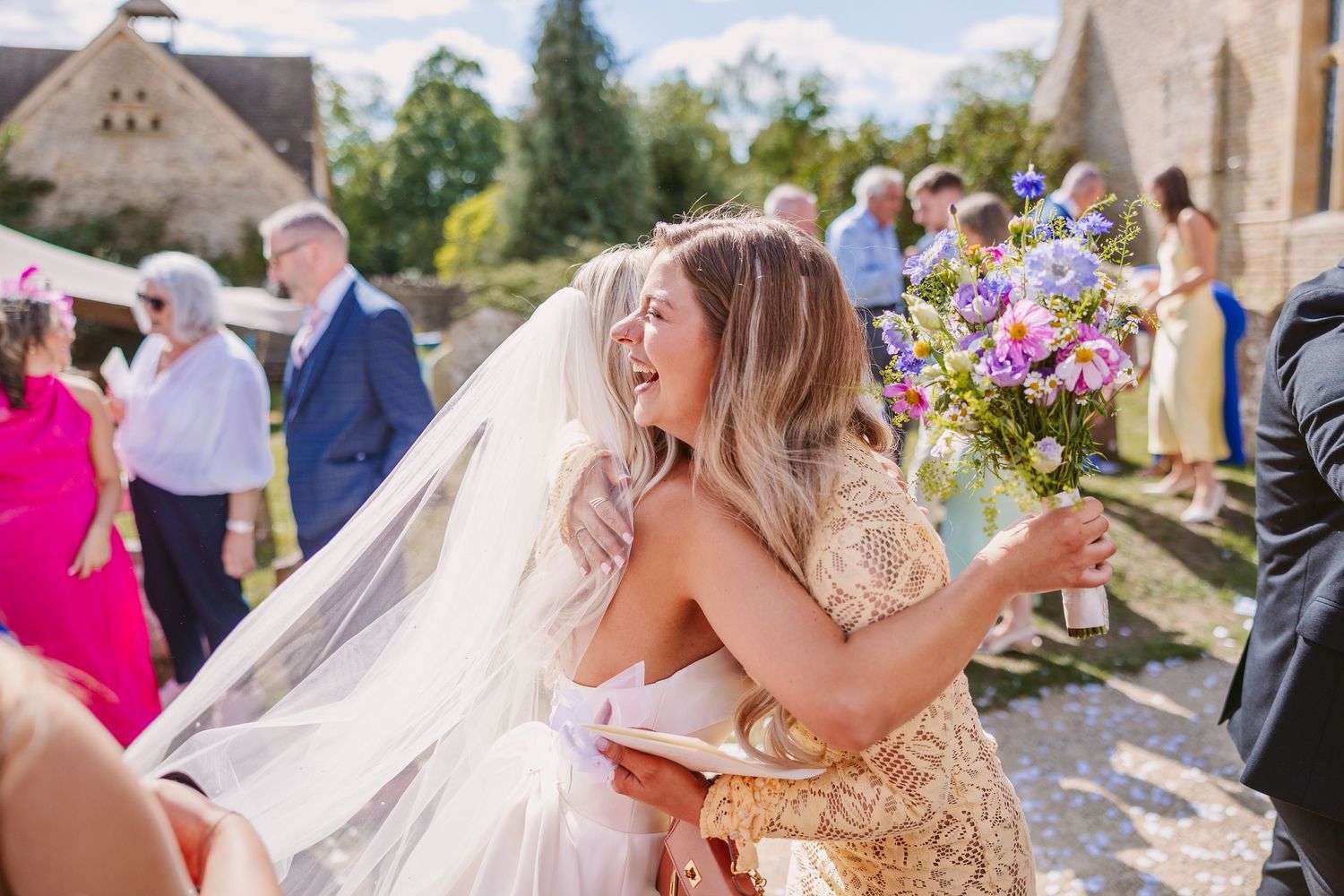 A joyful wedding celebration outside a stone church with a beautiful bouquet of colorful wildflowers.