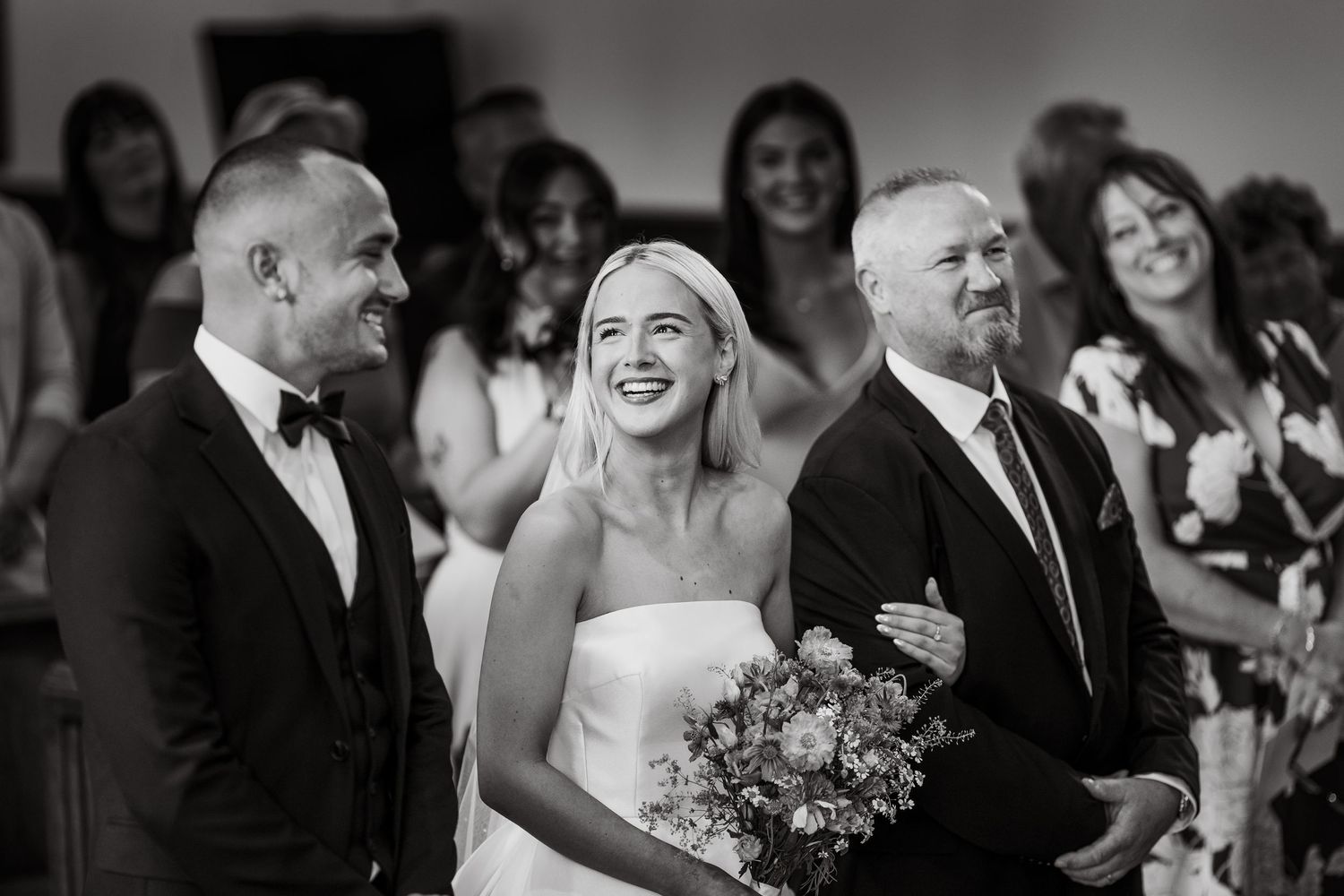 Wedding guests laugh and celebrate during an indoor reception.