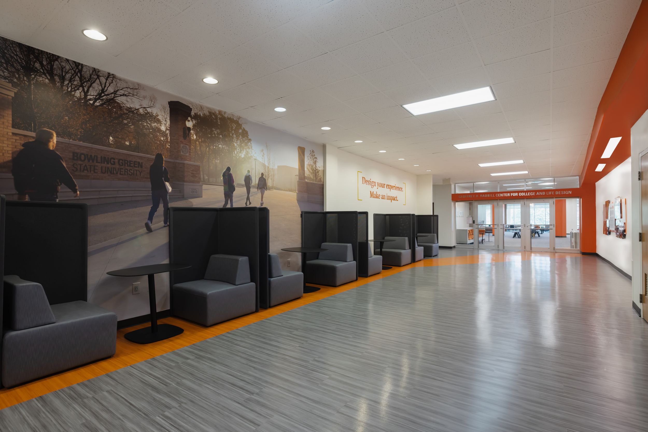 Modern office hallway with polished concrete floors, recessed lighting, and orange accent walls.