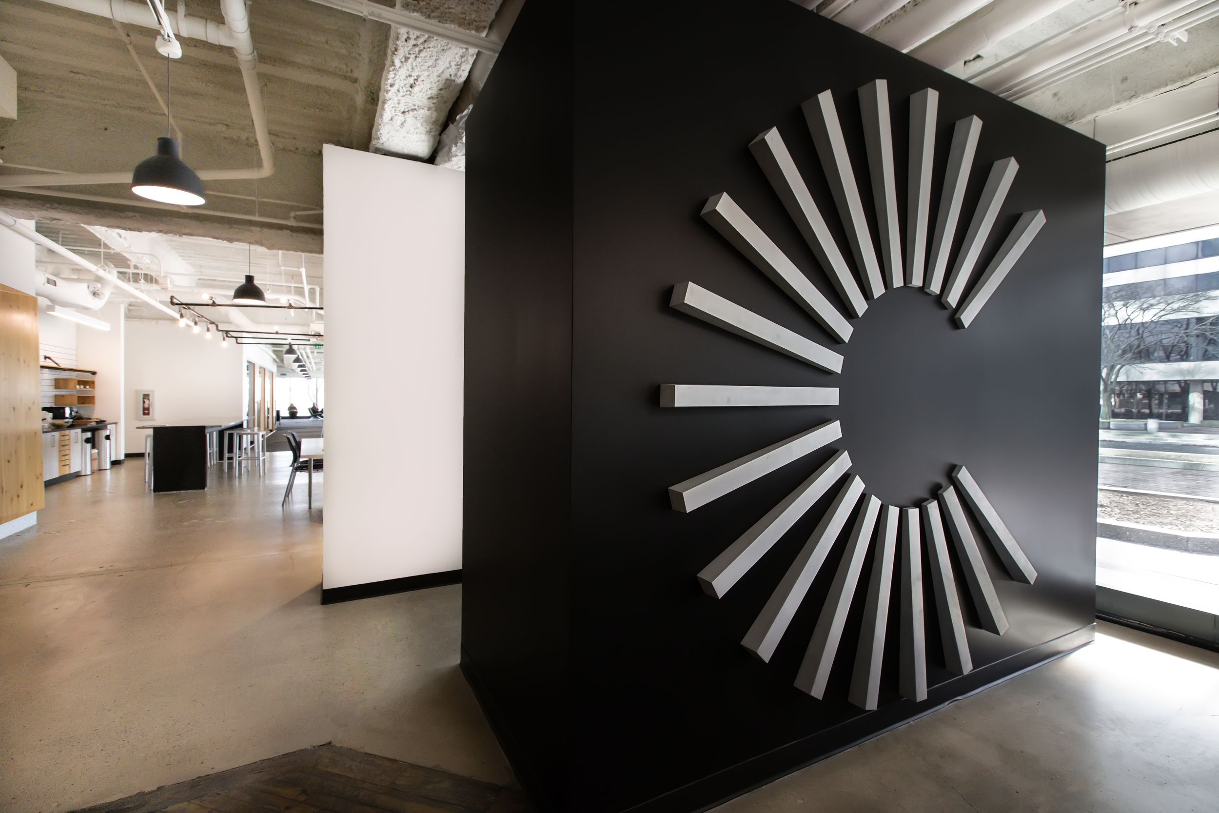 A series of connected gallery spaces with minimalist black and white geometric wall designs and industrial lighting.