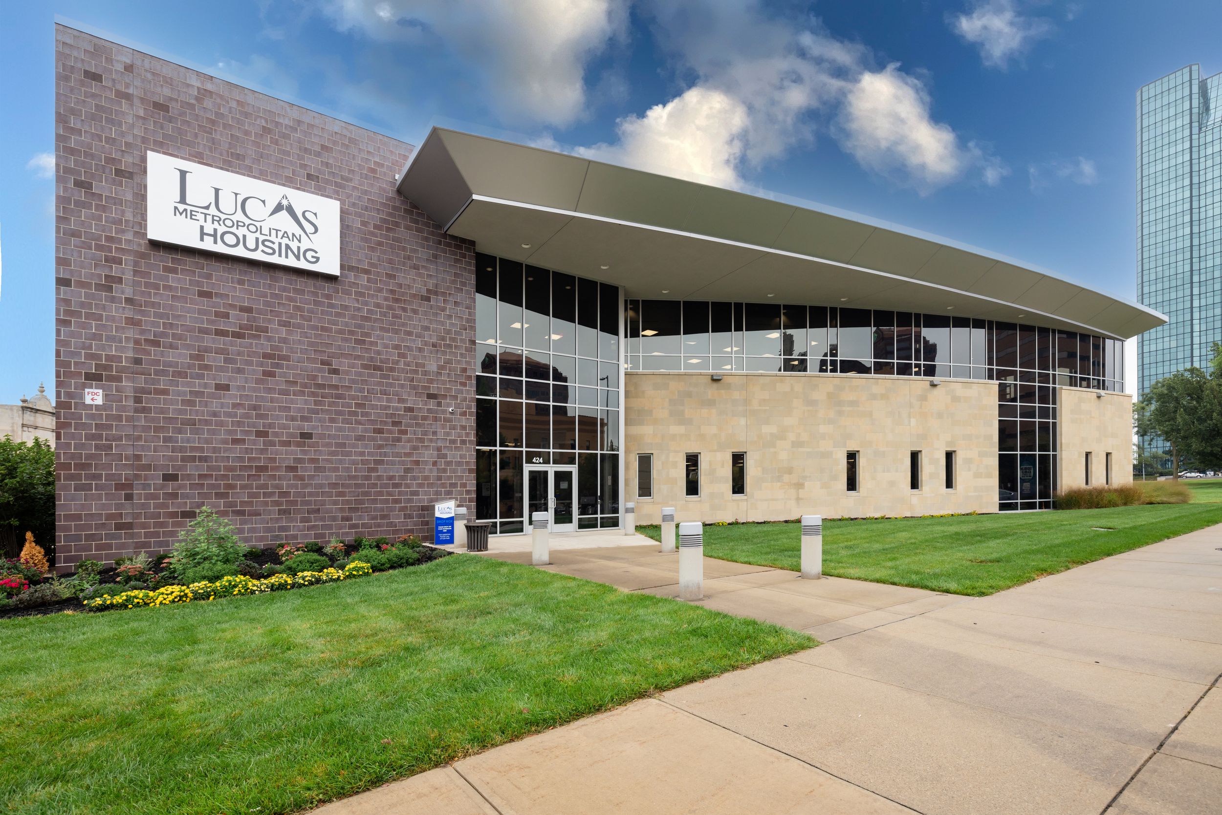 Exterior view of a modern brick building with glass windows and concrete walkways under blue skies.
