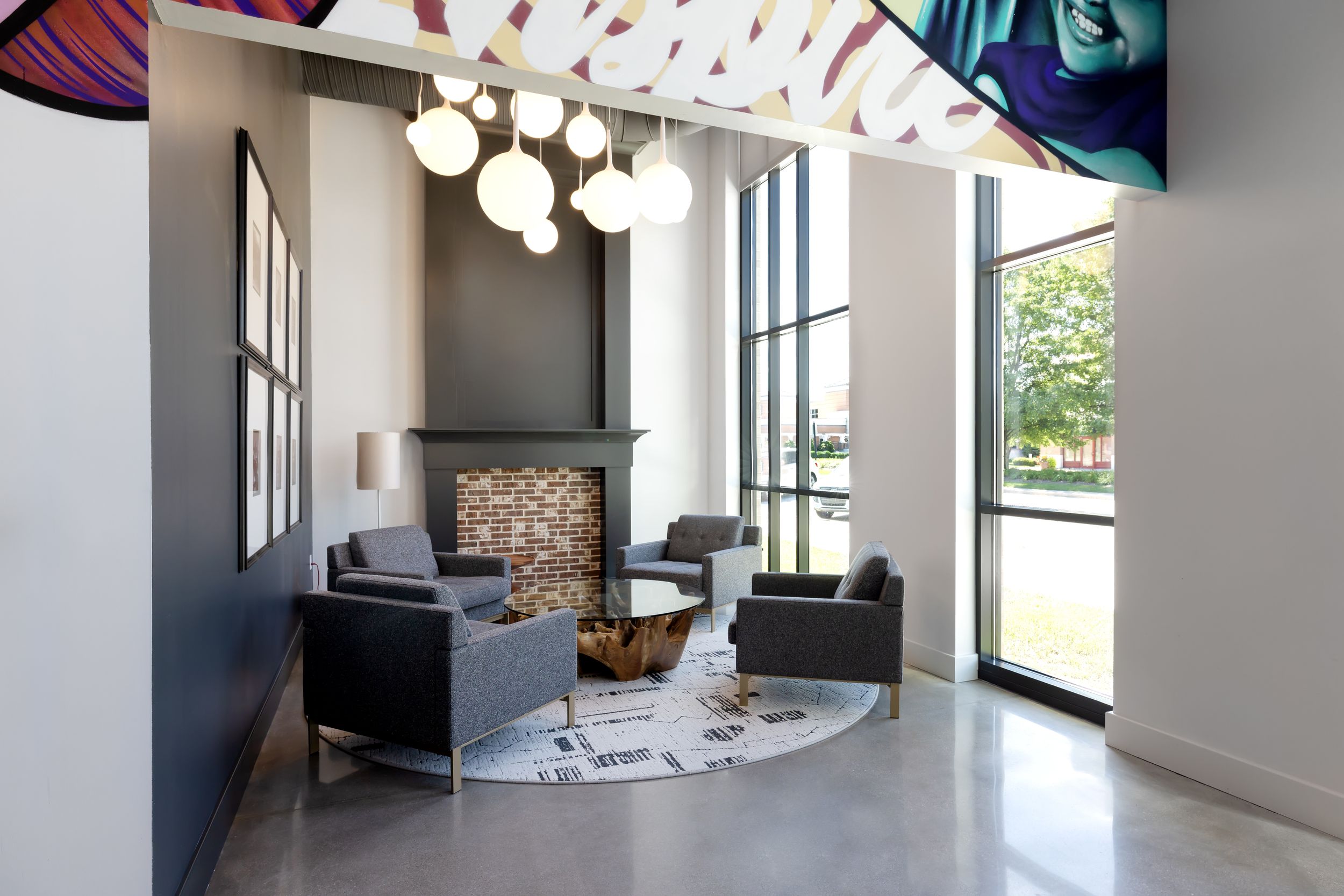 Modern office interior featuring large windows, pendant lighting, and sleek furniture in an open concept space.