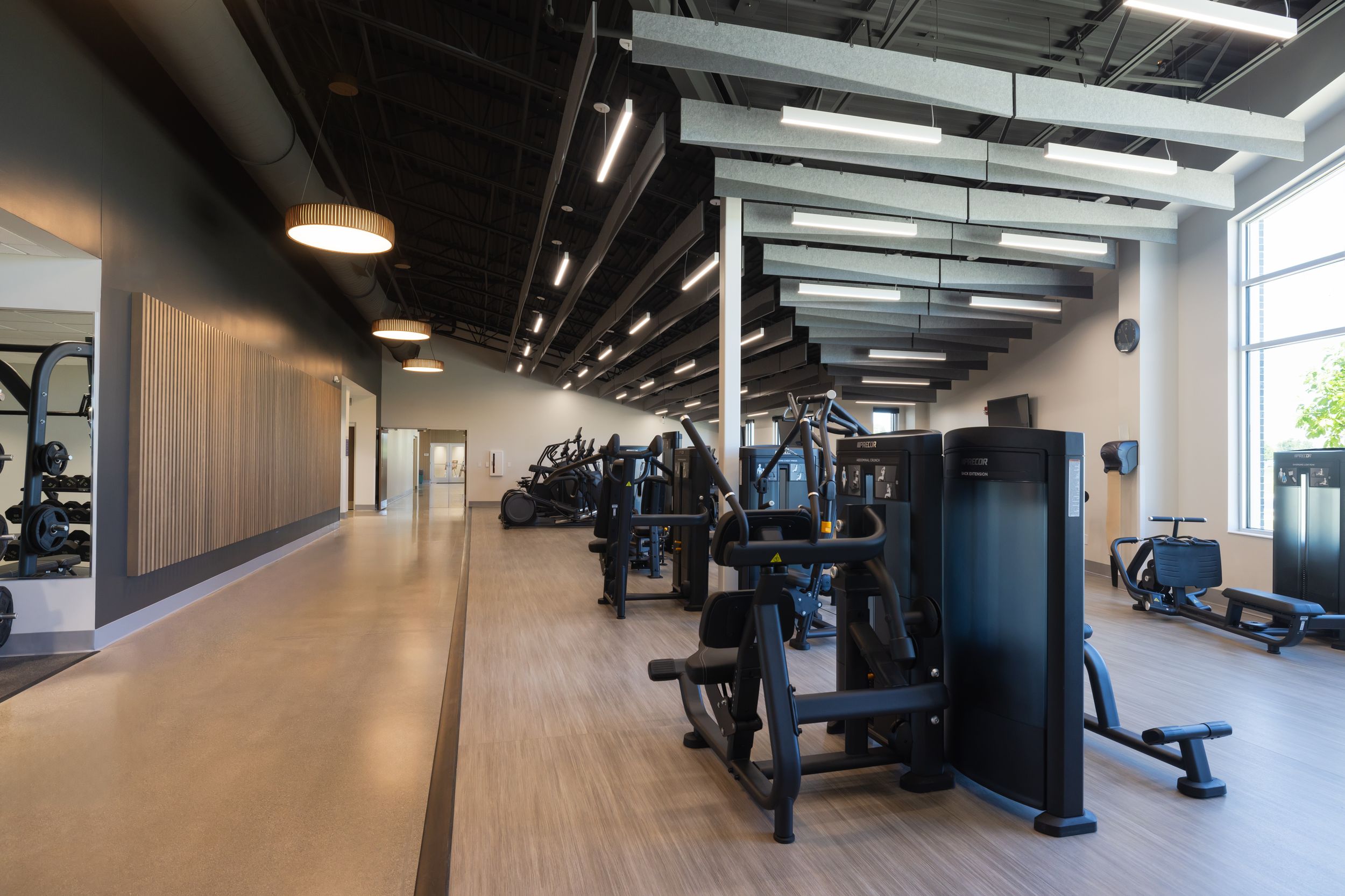 Modern fitness facility interior with black equipment and natural lighting through large windows.